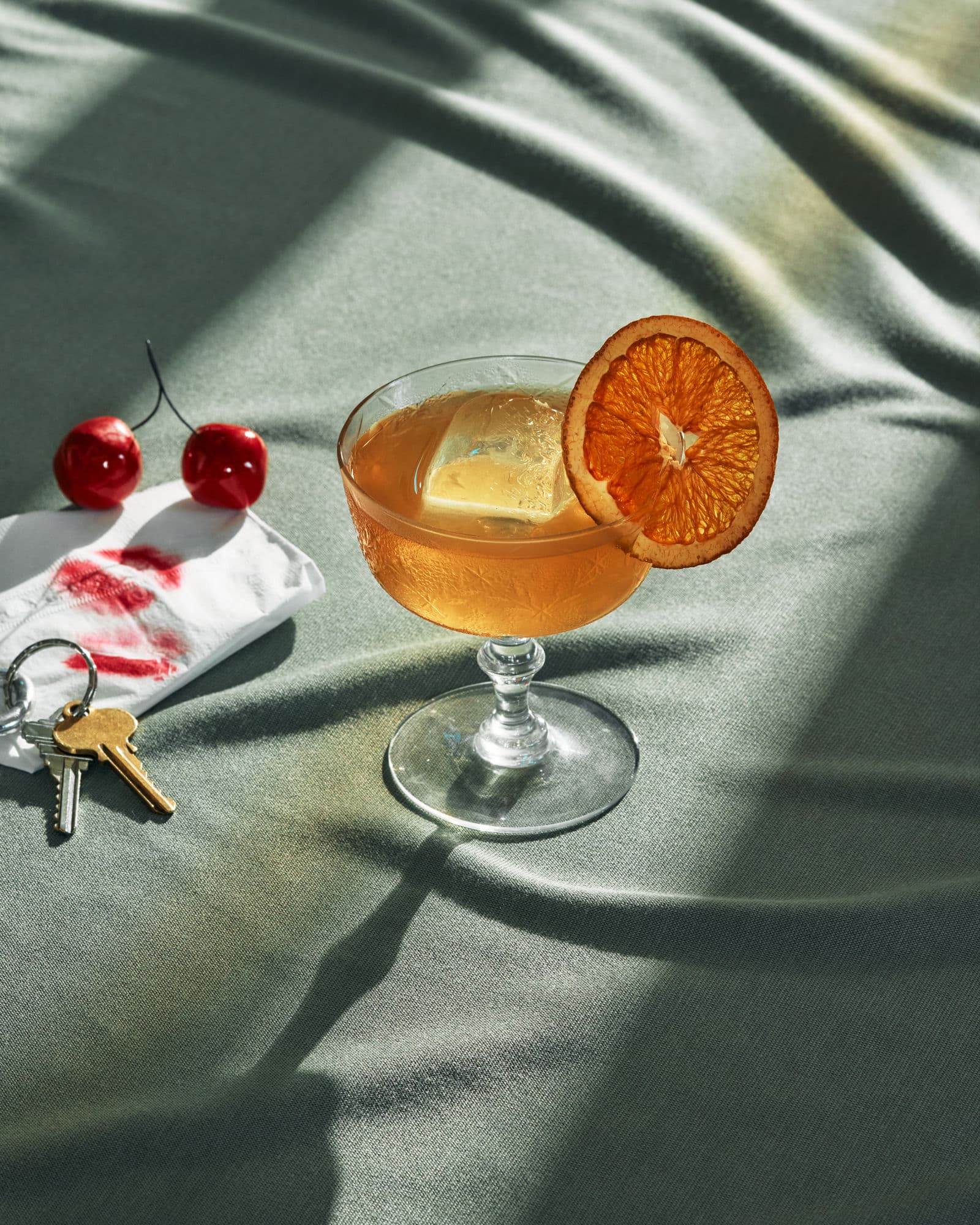 Amber coupe with dried orange slice and cherries on sage linen